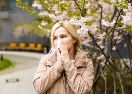 young-pretty-woman-sneezing-in-front-of-blooming-tree-spring-allergy-concept (1)
